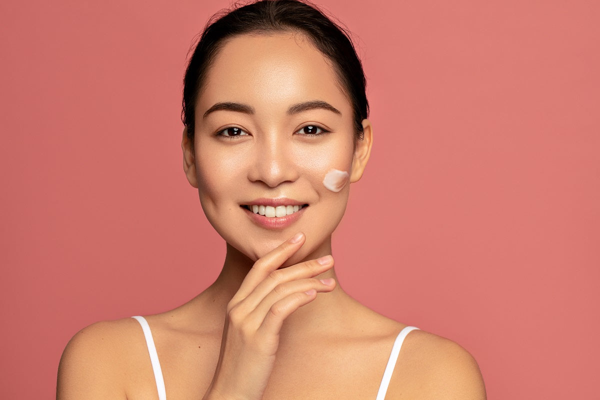 Young beautiful asian model posing with applayed cream on her face