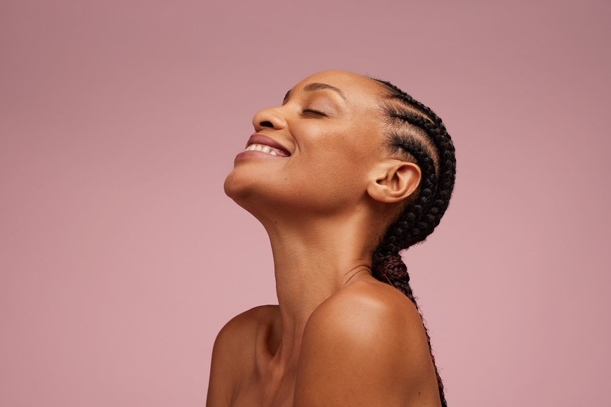 Woman with beautiful skin having braided hair smiling with eyes closed