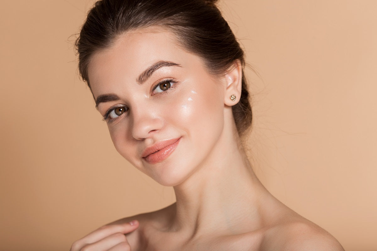 young woman with perfect skin with moisturizing face cream on a cheek